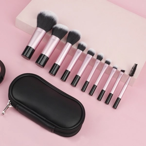 Detailed set of 10 pink makeup brushes with black zipper pouch on soft pink background