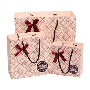 Set of three pink plaid paper gift bags with red satin bows and black nylon handles