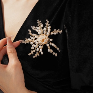 Detailed view of a handmade gold woven flower brooch with pearls on black velvet fabric