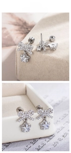 Macro detail of bowknot and star zircon pendant earrings with silver finish plating