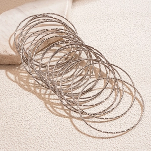 Dettaglio di 20 bracciali rigidi argentati a strati con finitura diamantata lucida