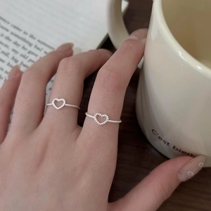 Detail of two silver heart rings on a model hand with a coffee mug background