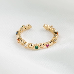 Macro view of 18K gold ring with multi-color zircon stones and heart shapes on white silk