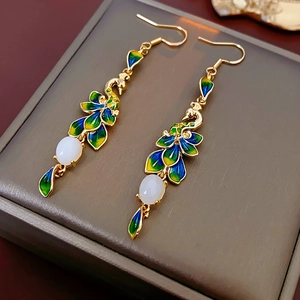 Dettaglio di orecchini a pavone placcati oro 14K con smalto e pietre ovali bianche
