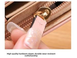 Close-up of golden metal zipper and pink lychee leather pull on a lady's long wallet