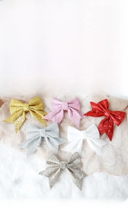 Glitter Christmas bow ornaments in six colors displayed on soft white snow background