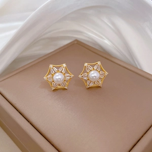 Macro shot of gold hexagon star earrings with white pearl and sparkling zircon inlay