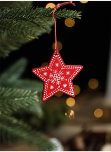 Macro shot of red wooden star ornament with snowflake patterns on a Christmas tree branch