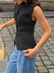 Detail of black knit sleeveless top with high neck and button closure on street model