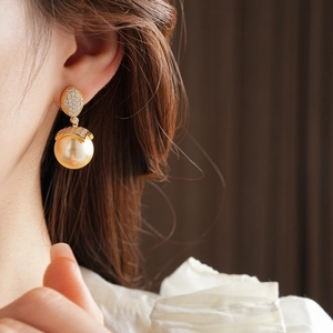Dettaglio di un orecchino placcato oro 18k con perla e cristalli indossato da modella