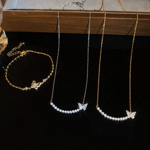Flat lay of 18k gold plated butterfly jewelry set with pearls and sparkling zircons
