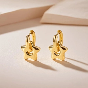 Macro detail of golden star pendant earrings with polished titanium steel finish