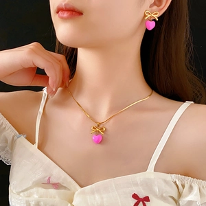 Gros plan d'un ensemble de bijoux nœud doré et cœur rose porté par un mannequin