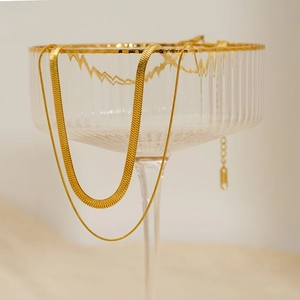 Double layer gold snake chain necklace in stainless steel shown on an elegant glass