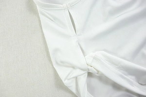 Detail view of white knitted fabric showing irregular hem and precision stitching quality