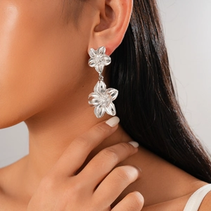 Close-up of double-layered silver flower earrings worn by a model in a side profile view