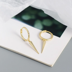 Macro shot of gold S925 silver hoop earrings with stylish cone-shaped spike pendants