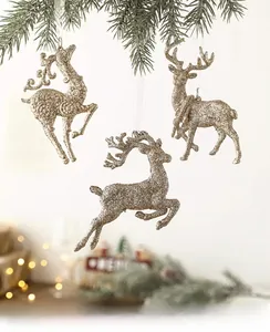 Detailed view of three golden glitter reindeer ornaments hanging on snow-covered pine branches