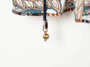 Détail de tissu imprimé ethnique et pendentif boule dorée sur une blouse décontractée