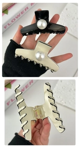 Detail view of large pearl claw clips in black and cream with wavy edge design