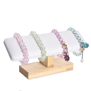 Solid wood bracelet stand with white padded bar displaying multi-colored beaded bracelets