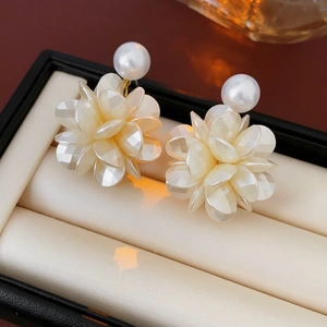 Détail de boucles d'oreilles fleur en acrylique avec perle dans un écrin