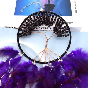 Detailed view of Tree of Life dream catcher with red stone beads and purple feathers