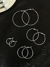 Detailed top view of four pairs of shiny silver hoop earrings in different sizes