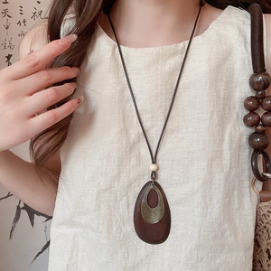 Detail view of ethnic wood waterdrop pendant with spiral metal textures on model