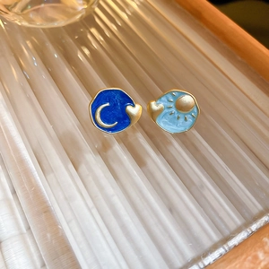 Detail of asymmetric sun and moon heart stud earrings with blue enamel finish