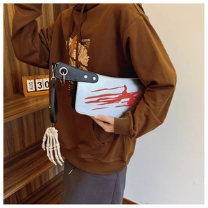Detail of cleaver-shaped handbag with blood splatter and white skeletal hand charm