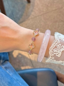Détail d'un bracelet trèfle en cristal rose associé à un jonc en quartz rose lisse