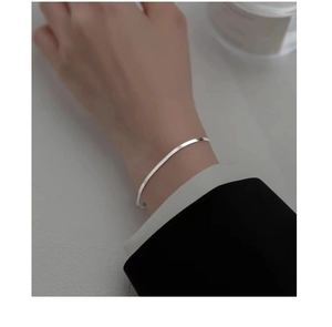 Close-up of minimalist S925 sterling silver flat snake chain bracelet on a wrist