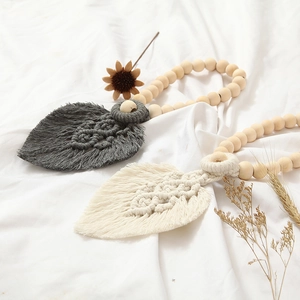 Detail of leaf macrame curtain tiebacks in grey and cream cotton rope with wooden beads