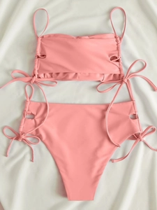 Detailed flat lay of pink bikini with side cutouts and decorative bow tie details