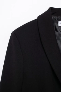 Close-up of black blazer shoulder and lapel detail showing fine fabric texture and cut
