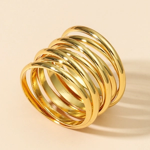 Polished gold multi-layer spiral ring with minimalist stackable design on beige background