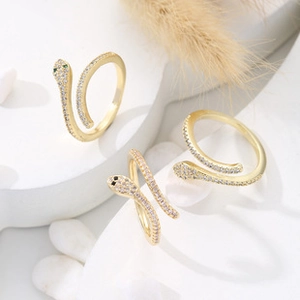 Detailed macro view of three gold snake-shaped open rings with pavé cubic zirconia