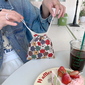 Floral corduroy drawstring pouch for cosmetics held in a cozy cafe setting
