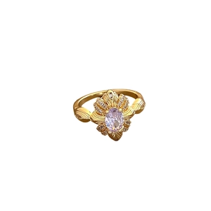 Vintage Goldring mit ovalem lila Edelstein und floralem Zirkon-Halo auf weißem Grund