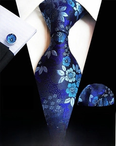 Macro view of dark blue floral silk tie and matching pocket square with cufflinks
