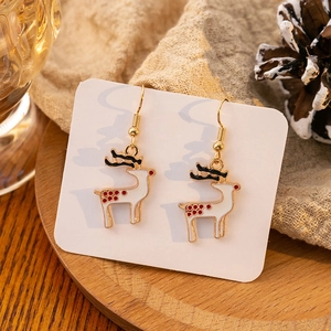 Detail view of festive reindeer earrings with red dots and gold hooks on wooden plate