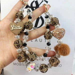 Detail of beaded bag charm with leopard print crystal, plush ball and heart pendants
