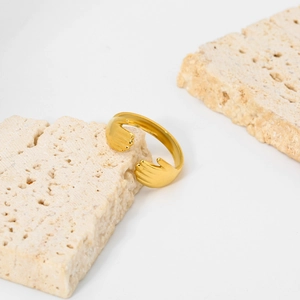 Gros plan d'une bague mains enlacées dorée sur des supports en travertin beige naturel