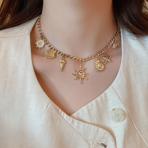 Detail of gold-plated ocean theme necklace with starfish and conch charms on model neck