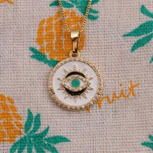 Détail du collier pendentif œil de démon doré avec émail blanc et pierres de zircon