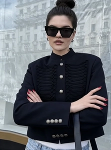 Detail of military style black cropped jacket with fringe and embossed metal buttons