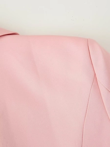 Detailed macro view of the shoulder seam and texture of a pink tailored blazer jacket