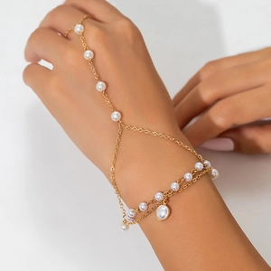 Detailed view of a gold chain hand harness with imitation pearls and rhinestone ring