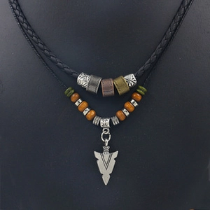Detail of layered ethnic necklace with sun pendant, beaded cords and arrow charm on bust